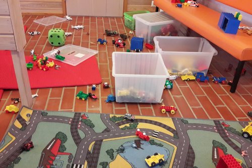 leikkiautoja, lelulaatikoita ja automatto lattialla