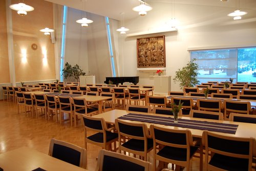 seurakuntakeskuksen sali. Pöytiä ja tuoleja, flyygeli, ikkuna