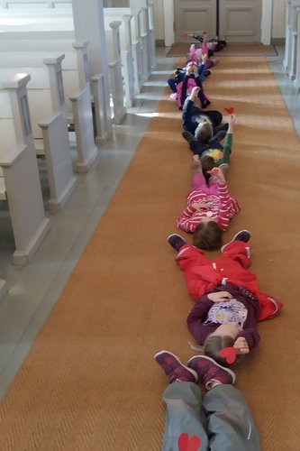 lapsia jonossa makaamassa kirkon keskikäytävällä